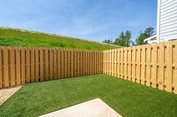 A backyard with a wooden fence and a green lawn.